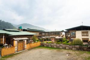 a group of buildings with a fence in front of it at Phuntsho Guest House in Jakar