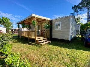 a tiny house with a porch and a deck at MOBIL-HOME "B30" tout confort avec piscine & lave-linge gratuit in Mimizan