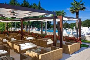 a pavilion with wicker chairs and tables next to a pool at Hotel Mediteran Plava Laguna in Poreč