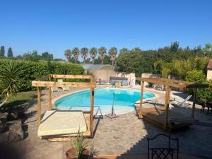 a swimming pool with a wooden canopy at Les Cigales in La Crau