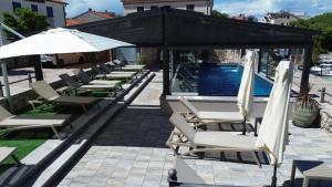 a row of lounge chairs and umbrellas next to a swimming pool at Villa Vista 1 in Malinska