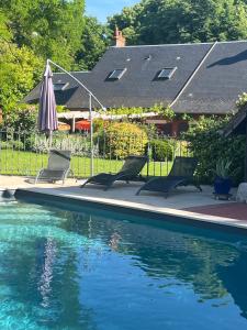 a swimming pool with two chairs and an umbrella at La MaiZon in Lazenay