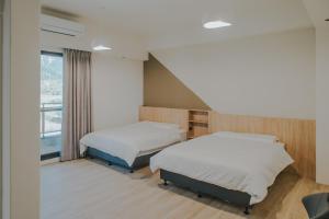a bedroom with two beds and a window at Chungi Hotel 純吉民宿 咖啡 in Xincheng