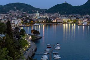 a group of boats in a river with a city at Hotel Borgo Antico in Como