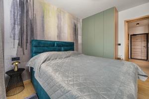 ein Schlafzimmer mit einem blauen Bett und einem Gemälde an der Wand in der Unterkunft Aine in Labin