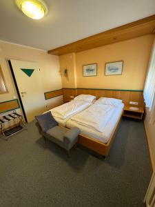 a bedroom with a large bed and a chair at Gästehaus Stögmüller in Asten