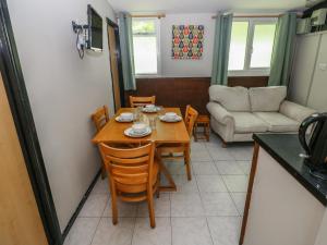 a dining room with a table and chairs and a couch at Cabin No 16 - Salt and Fern Cabins in Port Talbot +17 photos
