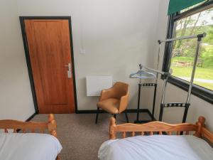 a room with two beds and a chair and a door at Cabin No 15 - Salt and Fern Cabins in Port Talbot