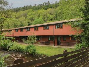 a red house with a fence and trees at Cabin No 15 - Salt and Fern Cabins in Port Talbot