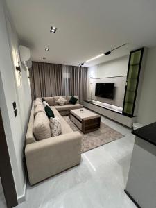 a living room with a couch and a tv at Hodoon Apartments in Amman