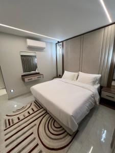 a bedroom with a large white bed and a rug at Hodoon Apartments in Amman