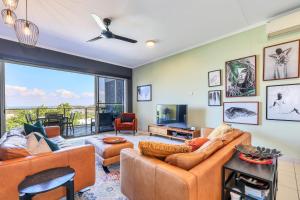 a living room with couches and a tv and a balcony at The Skyline Lookout Pool, BBQ, FREE parking in Stuart Park
