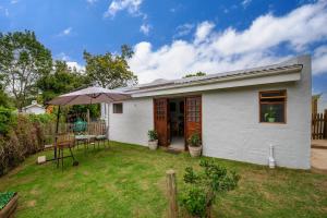 a small white house with a table and an umbrella at Disselblom Cottage in Sedgefield