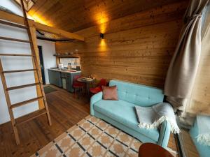 a living room with a blue couch and a kitchen at Merengő lombház in Nagymaros