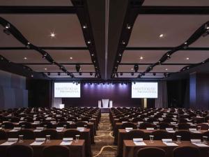 a conference room with tables and chairs and two screens at Novotel Ambassador Suwon in Suwon