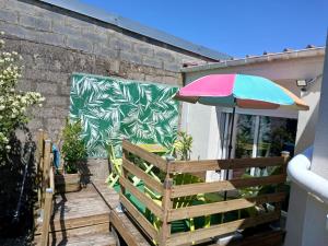 a patio with an umbrella and a wooden bench at Chez Isa in Saint-Martin-Boulogne