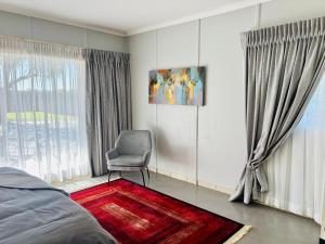 a bedroom with a chair and a window at Homestead in Kempton Park