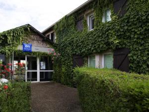 a building with ivy growing on the side of it at IBIS Budget Tarbes in Tarbes