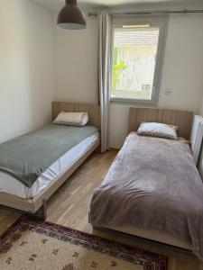 two beds in a room with a window at Résidence inside in Ferney-Voltaire