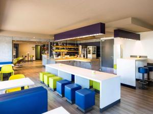 a kitchen with a white counter and colorful stools at ibis Budget Pau Est in Pau