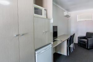 Habitación pequeña con escritorio y microondas. en Galaxy Mackay Motor Inn en Mackay
