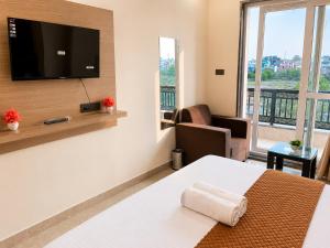 a hotel room with a bed and a flat screen tv at Hotel Pratishtha in Rishīkesh