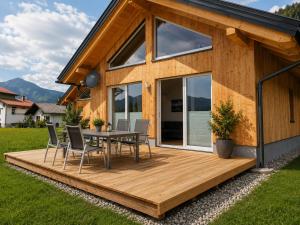 a wooden deck with a table and chairs on a house at Ferienhäuser Seetraum - Premium Card inklusive in Weissensee