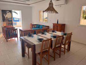 a dining room with a wooden table and chairs at Villa pieds dans l'eau, magnifique terrasse face à la mer in Zarzis