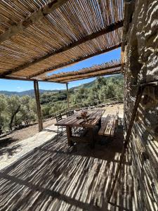 a wooden table on a wooden deck with a roof at Stazzu Pittorra per 4 persone in Barrabisa