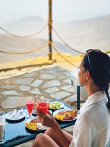 a woman sitting at a table with plates of food at SAMA Al Khutaim-Heritage Home in Nizwa