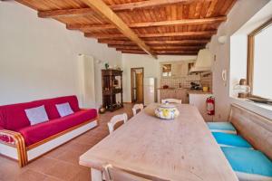 a living room with a wooden table and a red couch at Casa Cesare - appartamenti a Salina in Isola Salina
