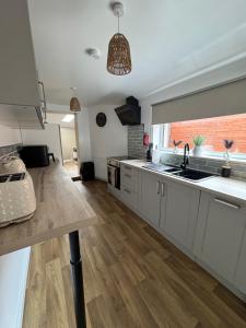 a kitchen with white cabinets and a large window at Gladstone Getaway in Peterhead +2 photos