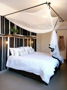 a bedroom with a white bed with a canopy at Birdsong Bungalow in Livingstone