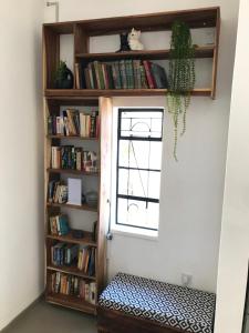 a room with a window and a book shelf with books at Birdsong Bungalow in Livingstone