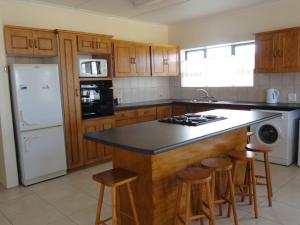 a kitchen with wooden cabinets and a island with bar stools at Berg En See in Kleinmond