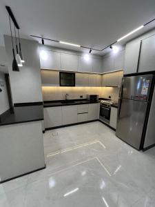 a large kitchen with white cabinets and stainless steel appliances at Hodoon Apartments in Amman +15 photos