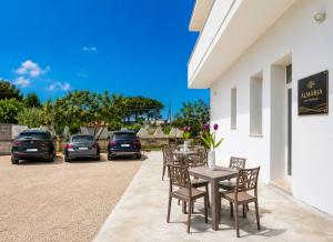 a table and chairs on a patio with parked cars at Almària - Rooms e Garden in Nardò