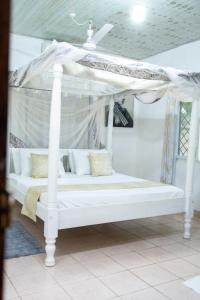 a white bed with a canopy in a room at Cosy Garner Haven Watamu in Watamu