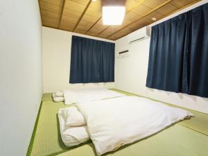 two beds in a room with blue curtains at Joynest TAKAMATSU in Takamatsu