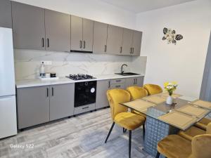 a kitchen with white cabinets and a table with yellow chairs at Apartament 3D in Fălticeni