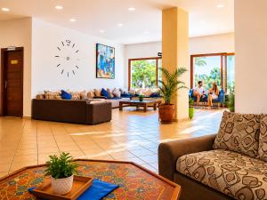 a living room with a couch and a clock on the wall at Appart Hôtel Cabo Dream in Cabo Negro