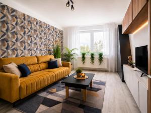 a living room with a yellow couch and a table at Comfort 65 2-Bedroom Apartment with Balcony in Miskolc