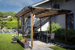 a wooden pergola with chairs and a table in a yard at Antares b&b in Cassina deʼ Pecchi