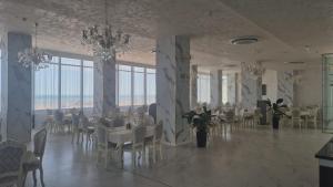 a dining room with white tables and chairs and windows at Hotel Alexandra in Mamaia
