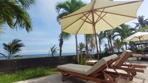 a couple of chairs and an umbrella and the ocean at Melaya Beach Resort Queen Bed in Penginuman