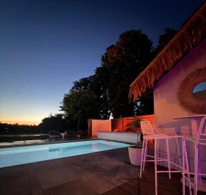 a patio with chairs and a swimming pool at night at Suite Vendôme - Elégance, Terrasse avec accès Piscine in Villeréal