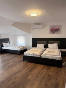 two beds in a room with wooden floors at Hotel Joana in Prizren