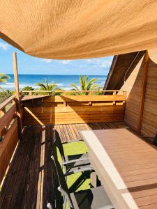 a wooden deck with a table and chairs on the beach at Grand Appartement - Pétrel 2 in Trois Bassins