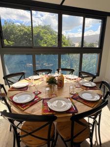 a wooden table with chairs and plates on it at Grand Appartement - Pétrel 2 in Trois Bassins
