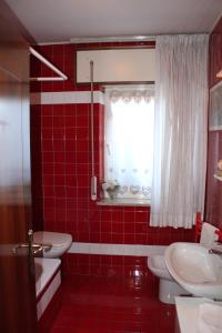 - une salle de bains carrelée de rouge avec 2 toilettes et une fenêtre dans l'établissement Kèbele, à Roana